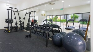 Een fitnessruimte met gewichthefapparatuur, loopbanden en oefenballen.