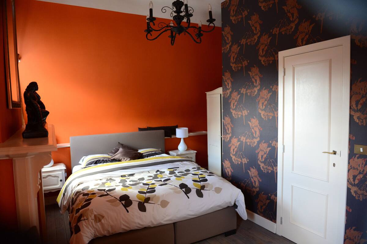 A bedroom with a bed, a nightstand, a dresser, and a door.