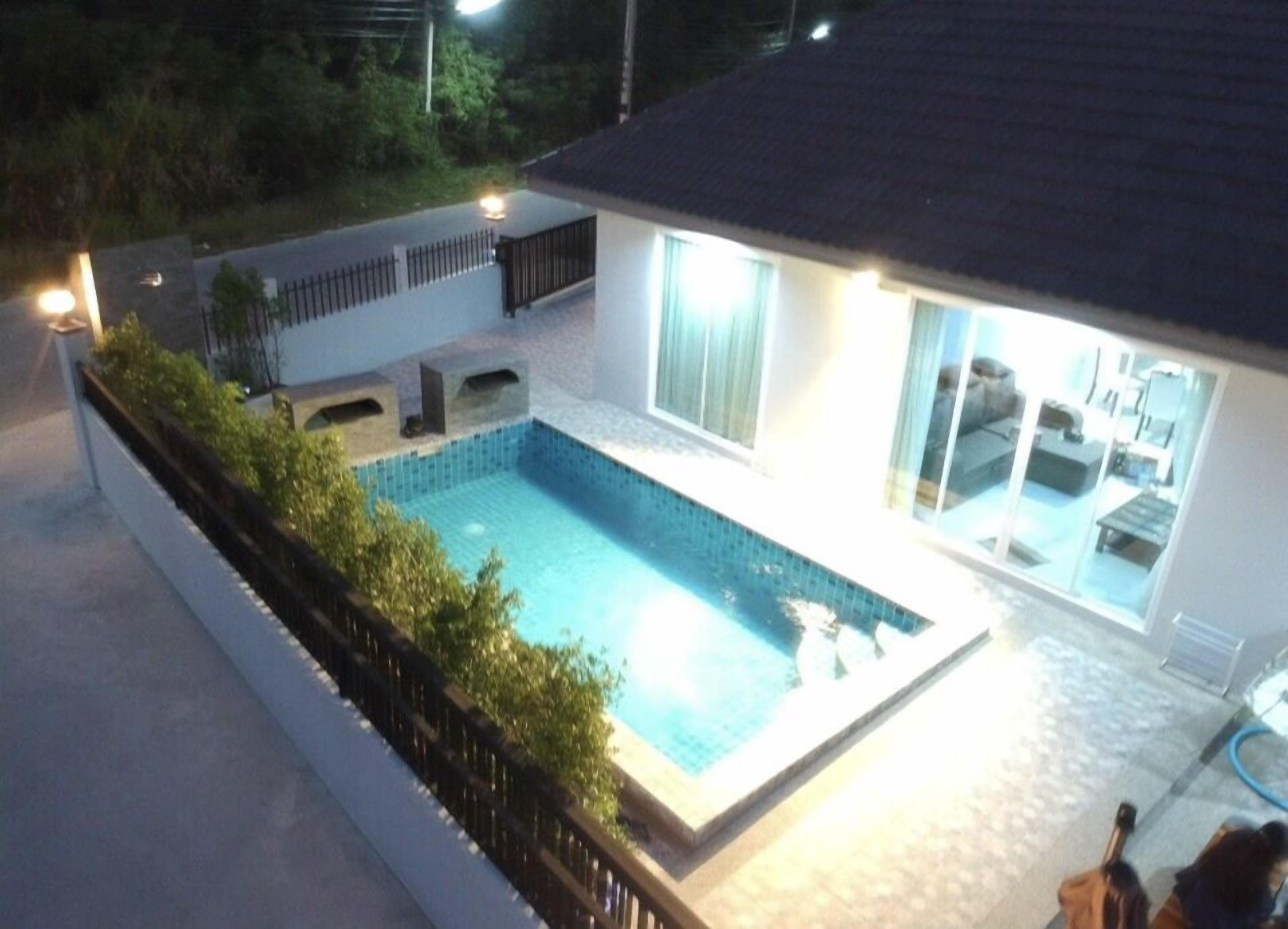 Une maison moderne dotée d’une piscine, d’un patio couvert et d’un espace de vie ouvert comprenant un canapé et une table à manger.