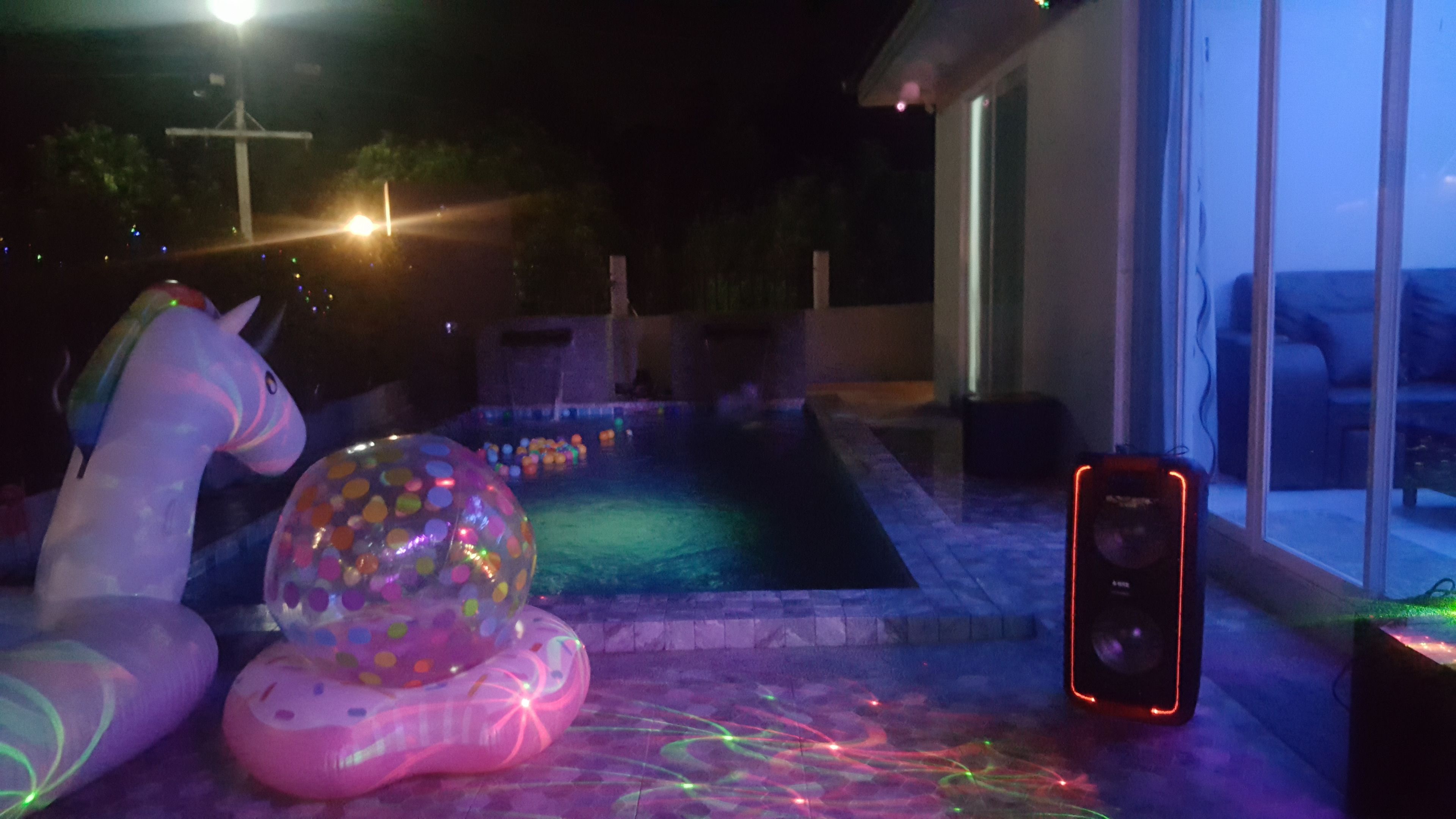 Ein Poolbereich mit Einhorn-Dekoration, einem großen Luftballon und einem Smartphone am Boden.