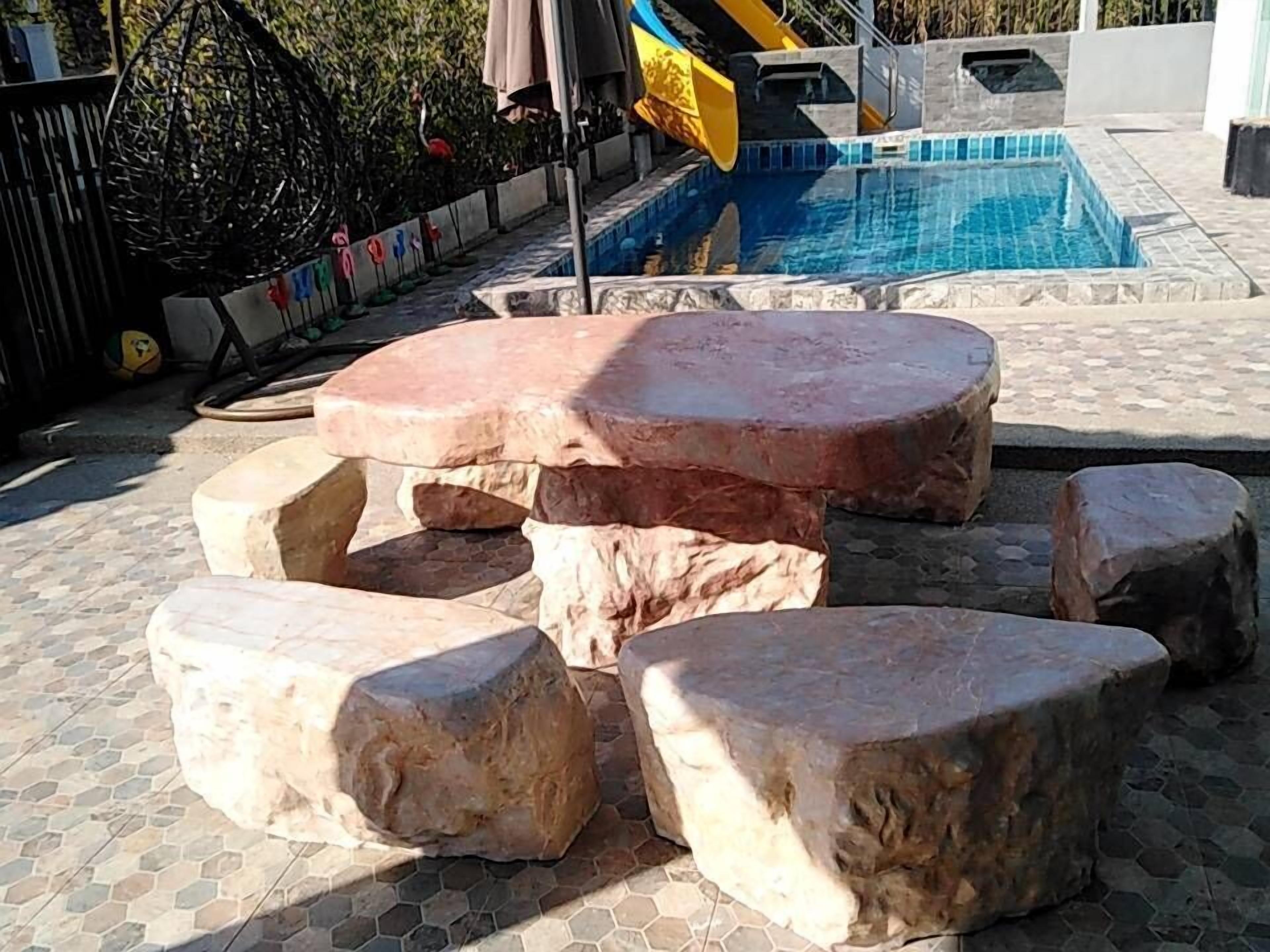 Zona de piscina con un espacio de asientos de piedra y un tobogán.