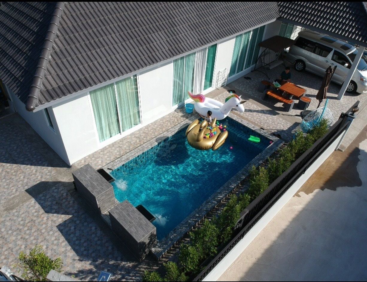 A swimming pool with a unicorn float, a patio area with a table and chairs, and a car parked nearby.