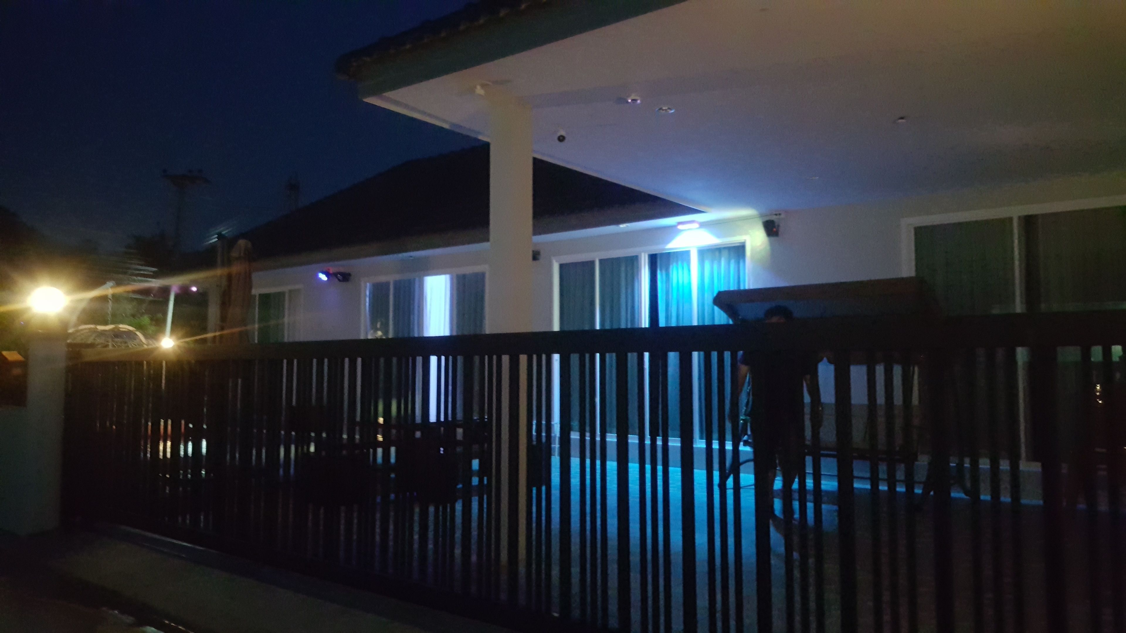 A residential building with a fenced yard, a visible pool, and a balcony.