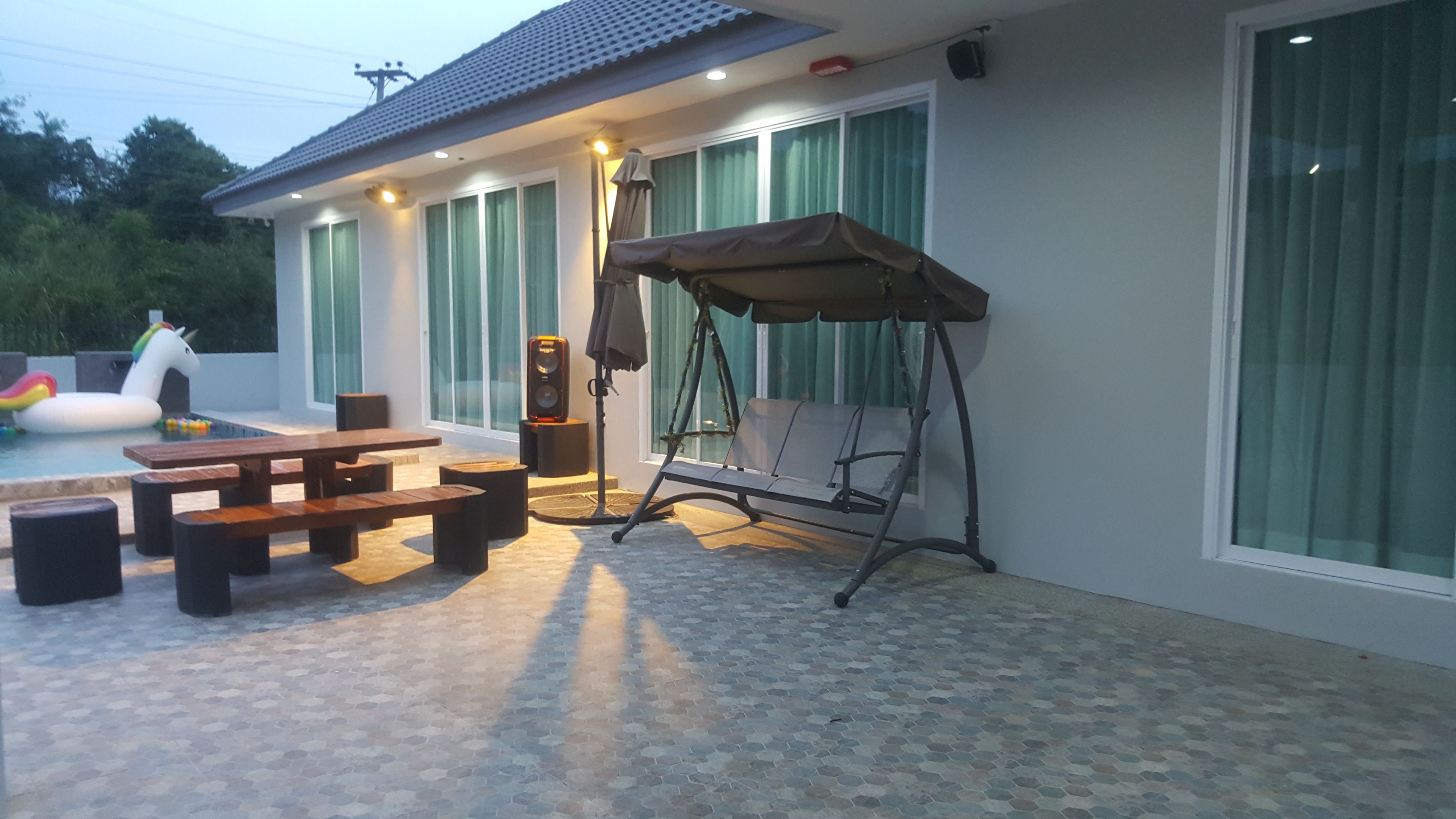 Un patio exterior con una mecedora, una piscina y una mesa de picnic.