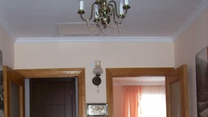 A hallway with a chandelier, a wooden door, a framed picture, and a patterned rug. - Sweet Home (Kazbegi)