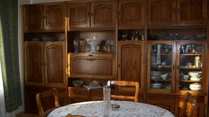 A dining room with wooden cabinets, a lace tablecloth, and a crystal vase. - Sweet Home (Kazbegi)