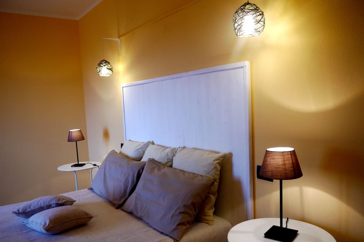 A bedroom with a bed, two bedside tables, and two wall-mounted lamps.