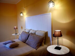 Un dormitorio con una cama, dos mesitas de noche y dos lámparas de pared.