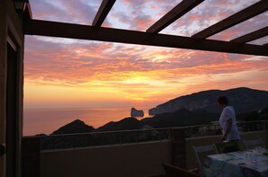 Vista del atardecer desde un balcón con una mesa lista para cenar.