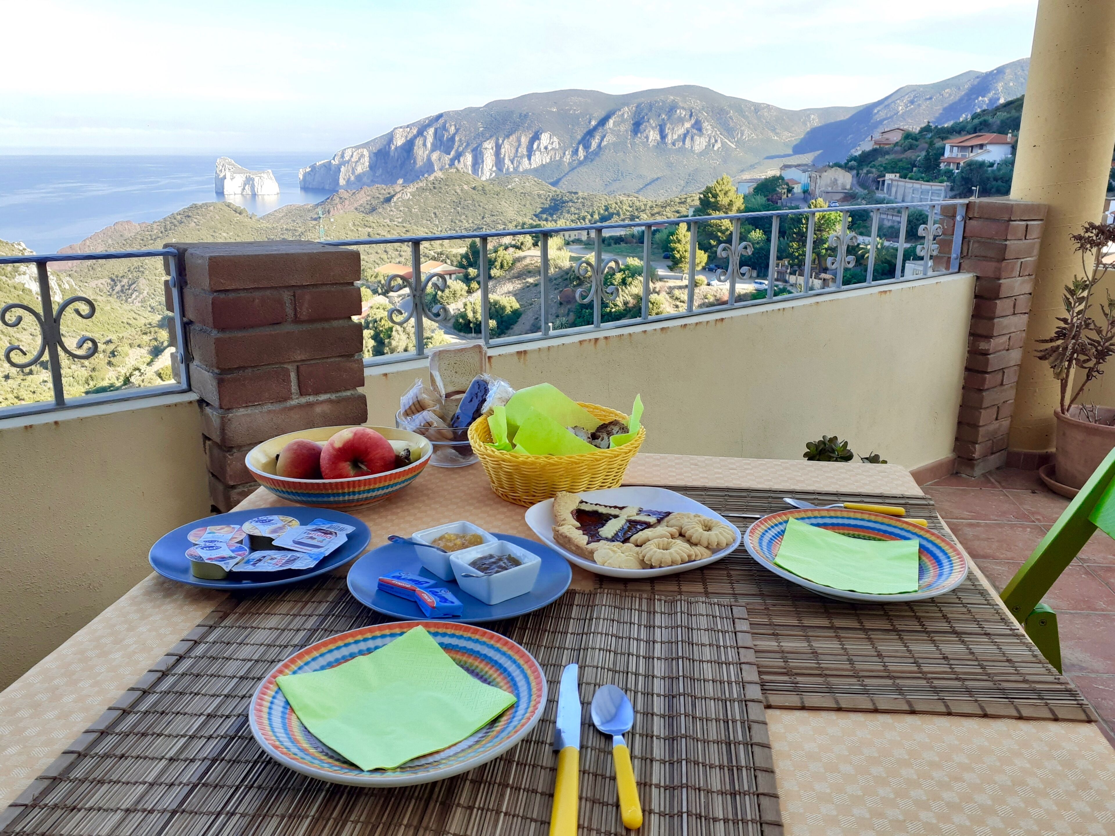 Un balcone con un tavolo apparecchiato per la colazione, con vista su un paesaggio montano.