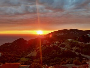 Atardecer sobre un paisaje montañoso con edificios y una carretera.