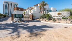 A modern hotel entrance with a stone facade, a palm tree, and a clear blue sky. - Luna Blanca 0801-2BR by Kivoya (Puerto Peñasco)