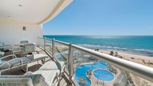 A balcony with lounge chairs and a pool area, overlooking a beach and ocean. - Luna Blanca 0801-2BR by Kivoya (Puerto Peñasco)