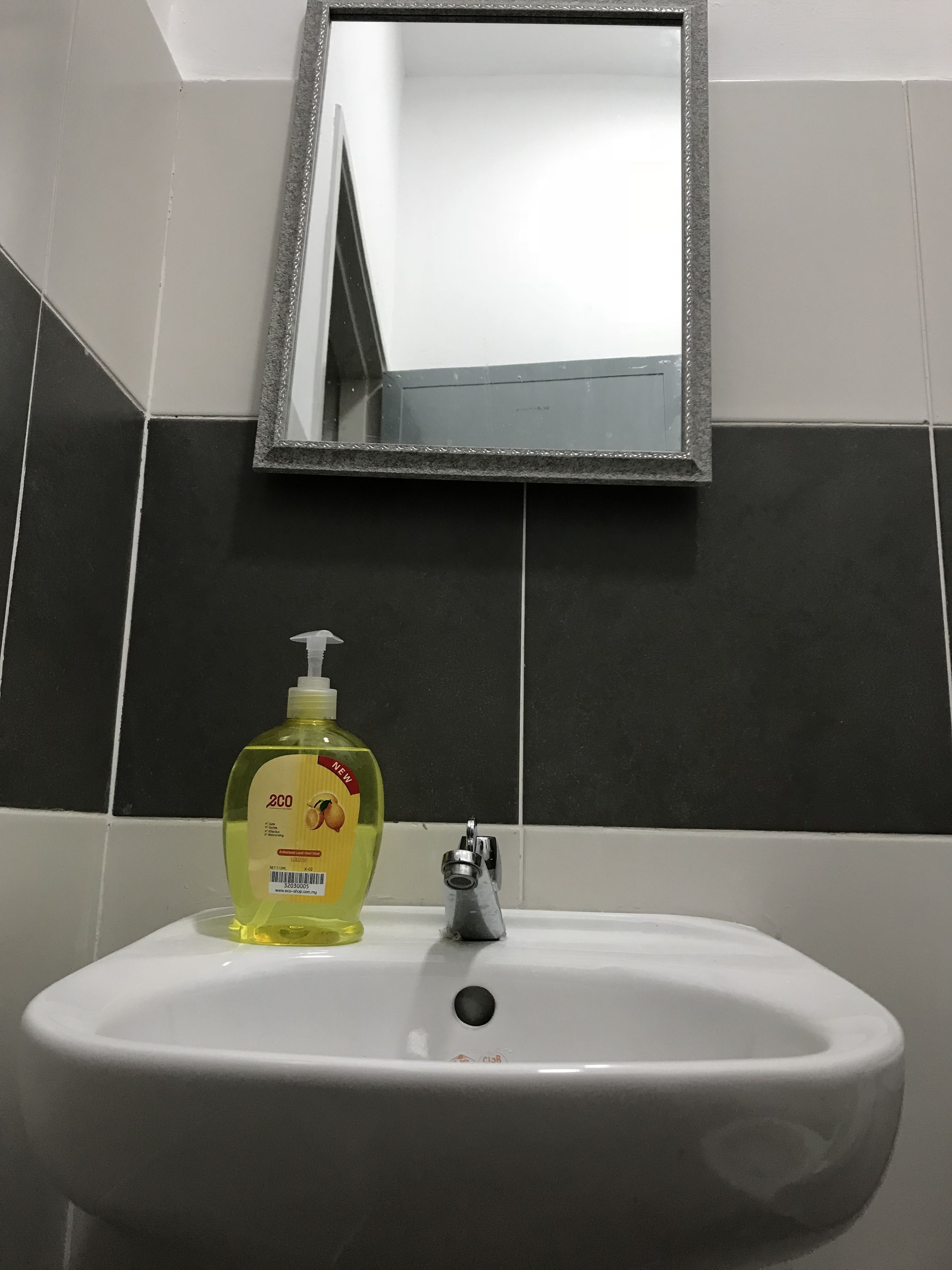 A bathroom sink with a mirror above it, a bottle of liquid soap, and a faucet.