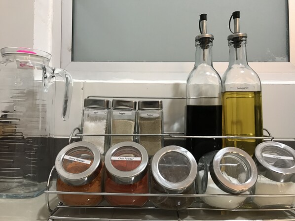 Een kruidenrek met containers met etiketten voor zout, peper, currypoeder en chilipoeder.