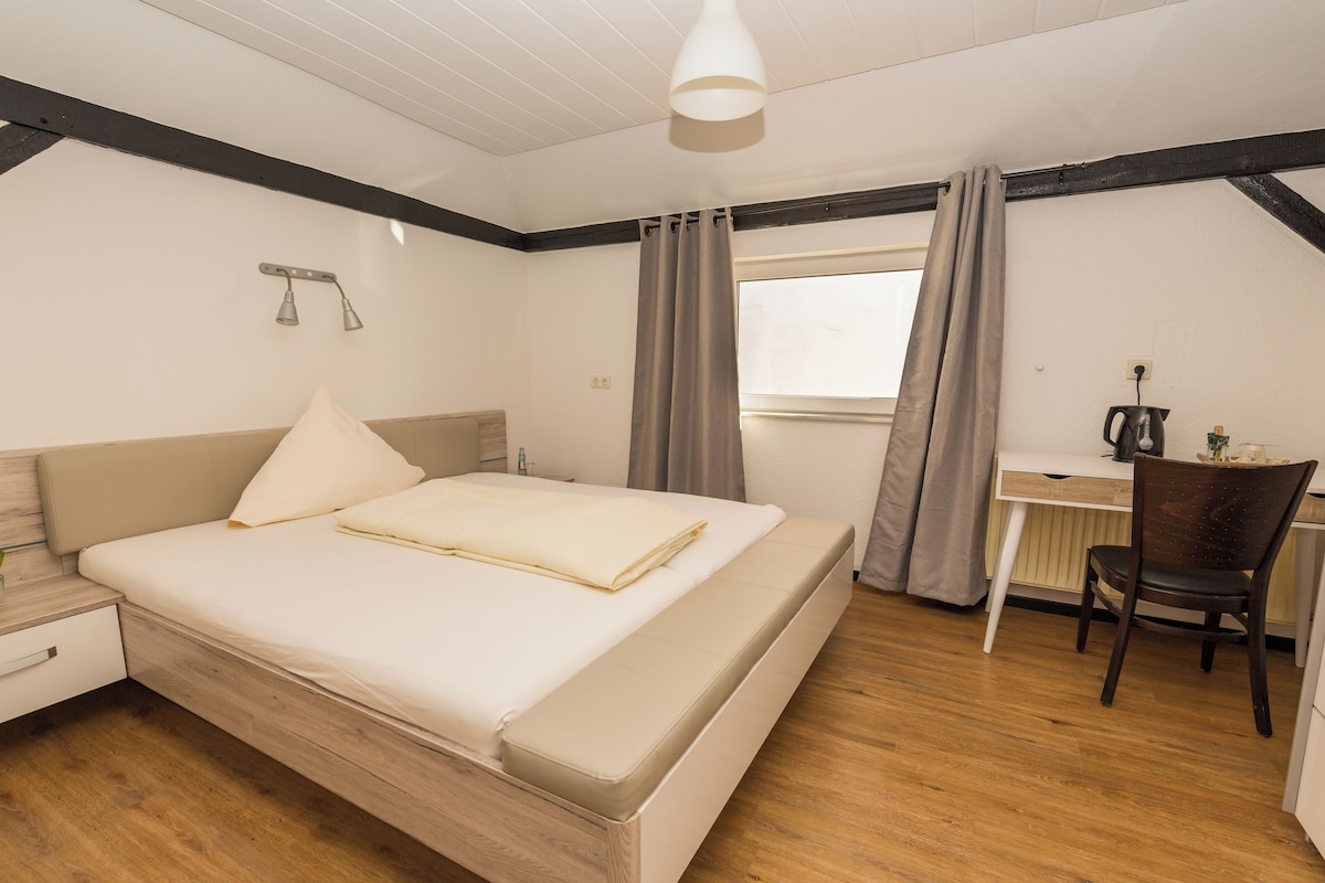 A bedroom with a bed, a desk, and a chair.