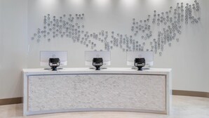 Un mostrador de recepción con tres monitores HP, un papel tapiz estampado y un techo con iluminación empotrada.