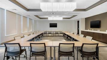 A conference room with a long table, chairs, a television, and a modern ceiling design.