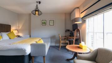 Une chambre d’hôtel avec un lit, un bureau, une chaise, une lampe et une fenêtre.