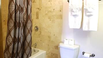 A bathroom with a bathtub, toilet, and shower curtain.