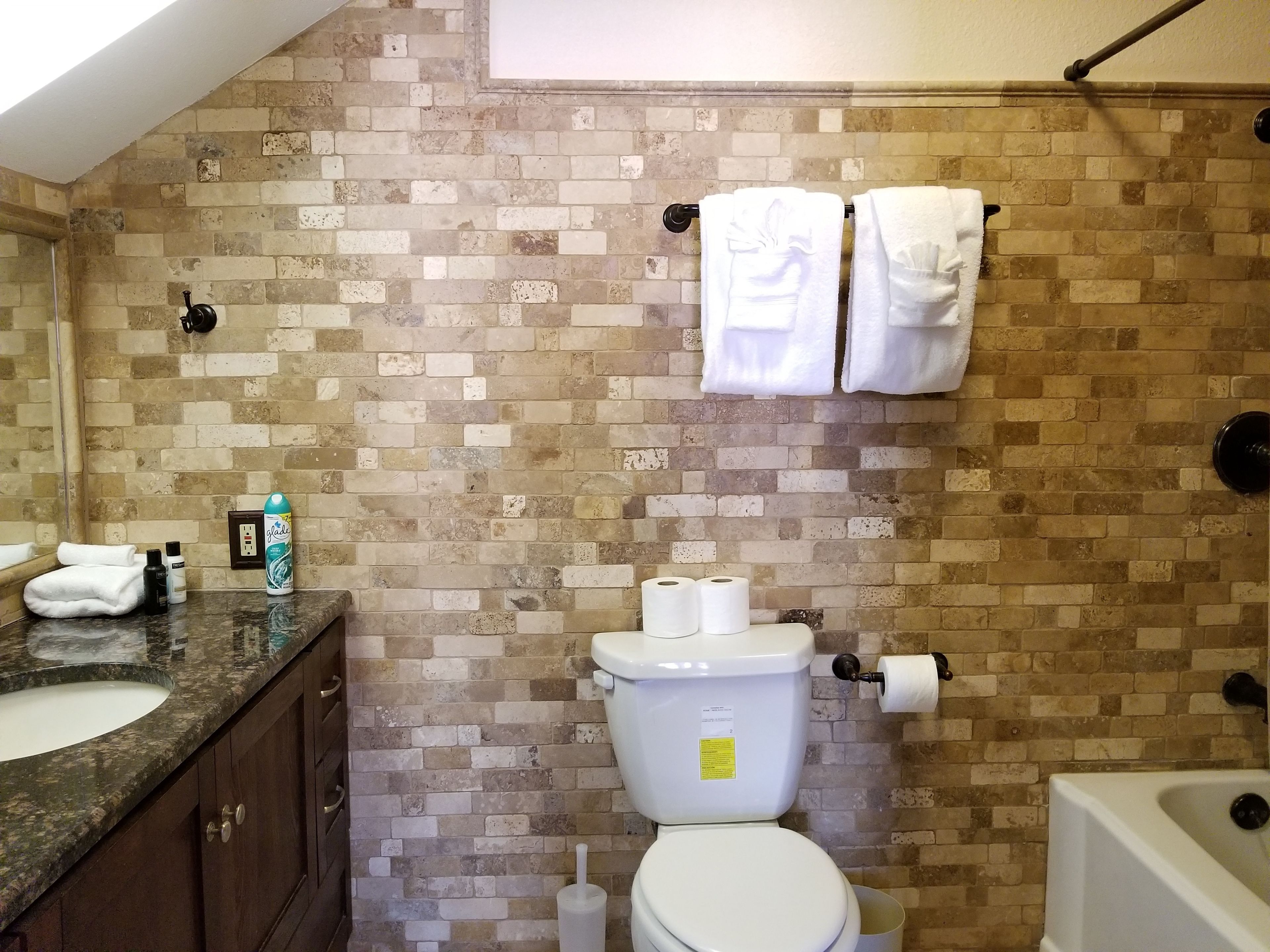 Une salle de bain avec un mur carrelé, des toilettes, un lavabo et une baignoire.