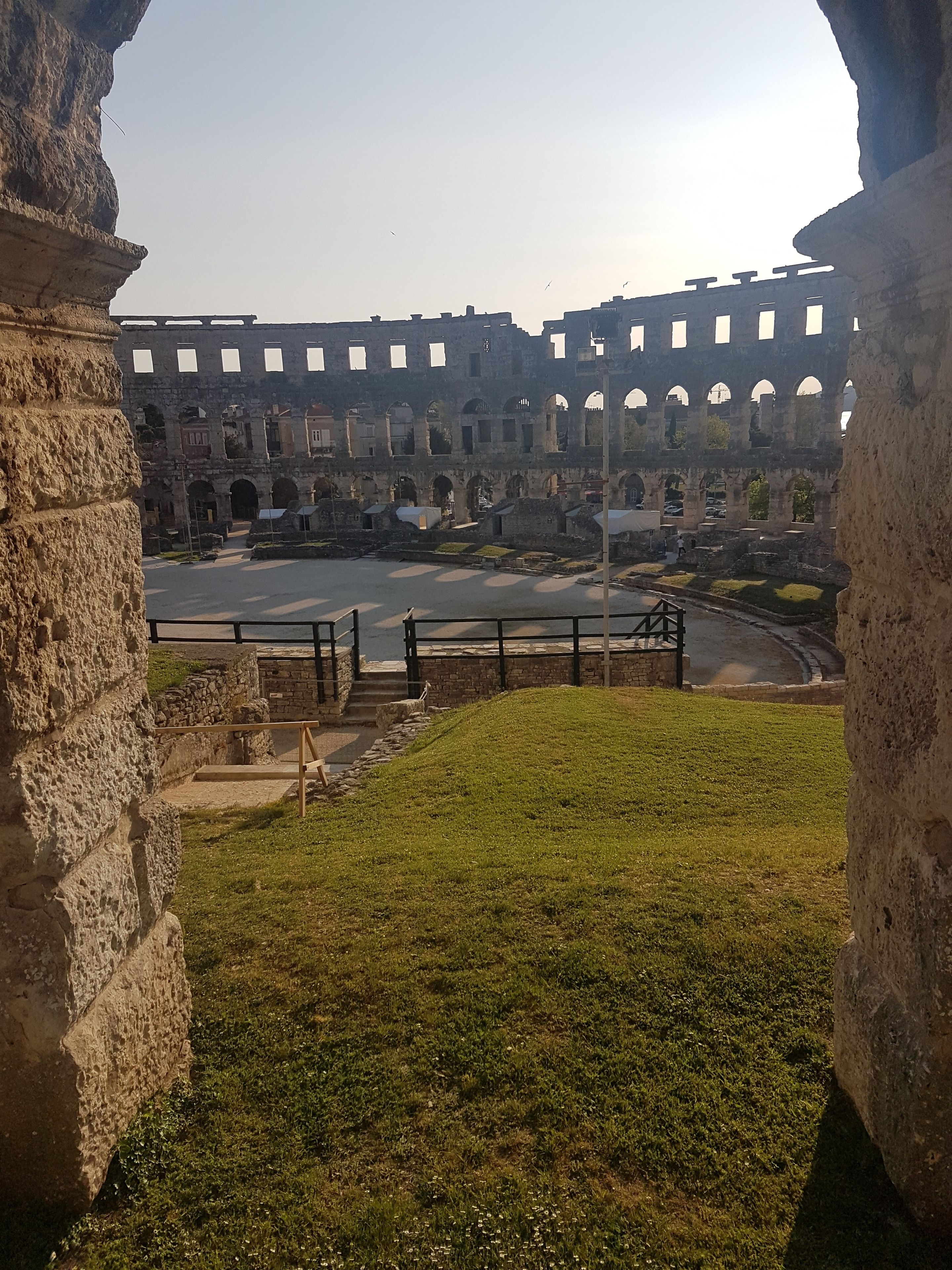 An ancient Roman amphitheater with stone arches and a central open area.