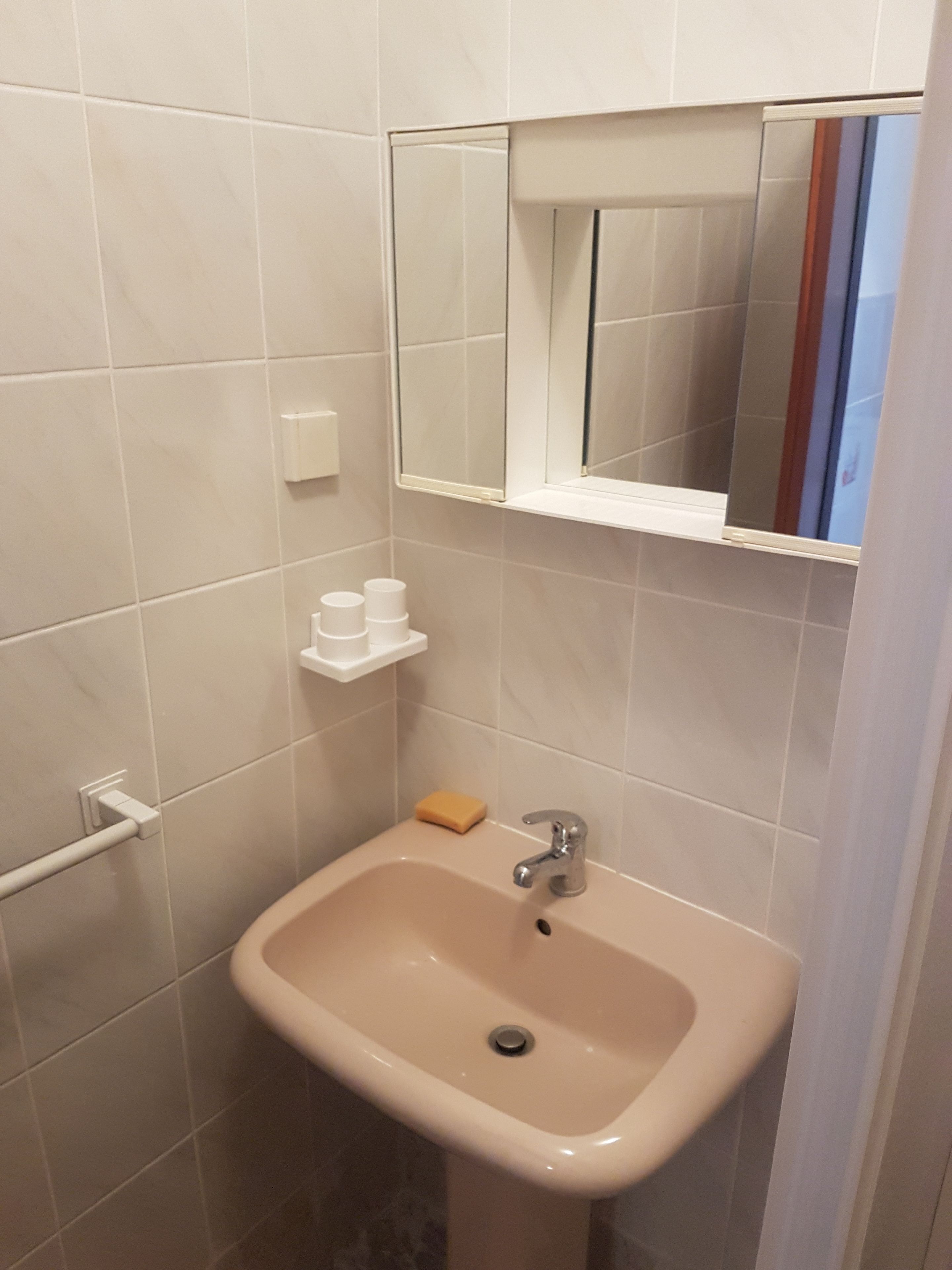 A bathroom with a sink, mirror, and storage shelves.