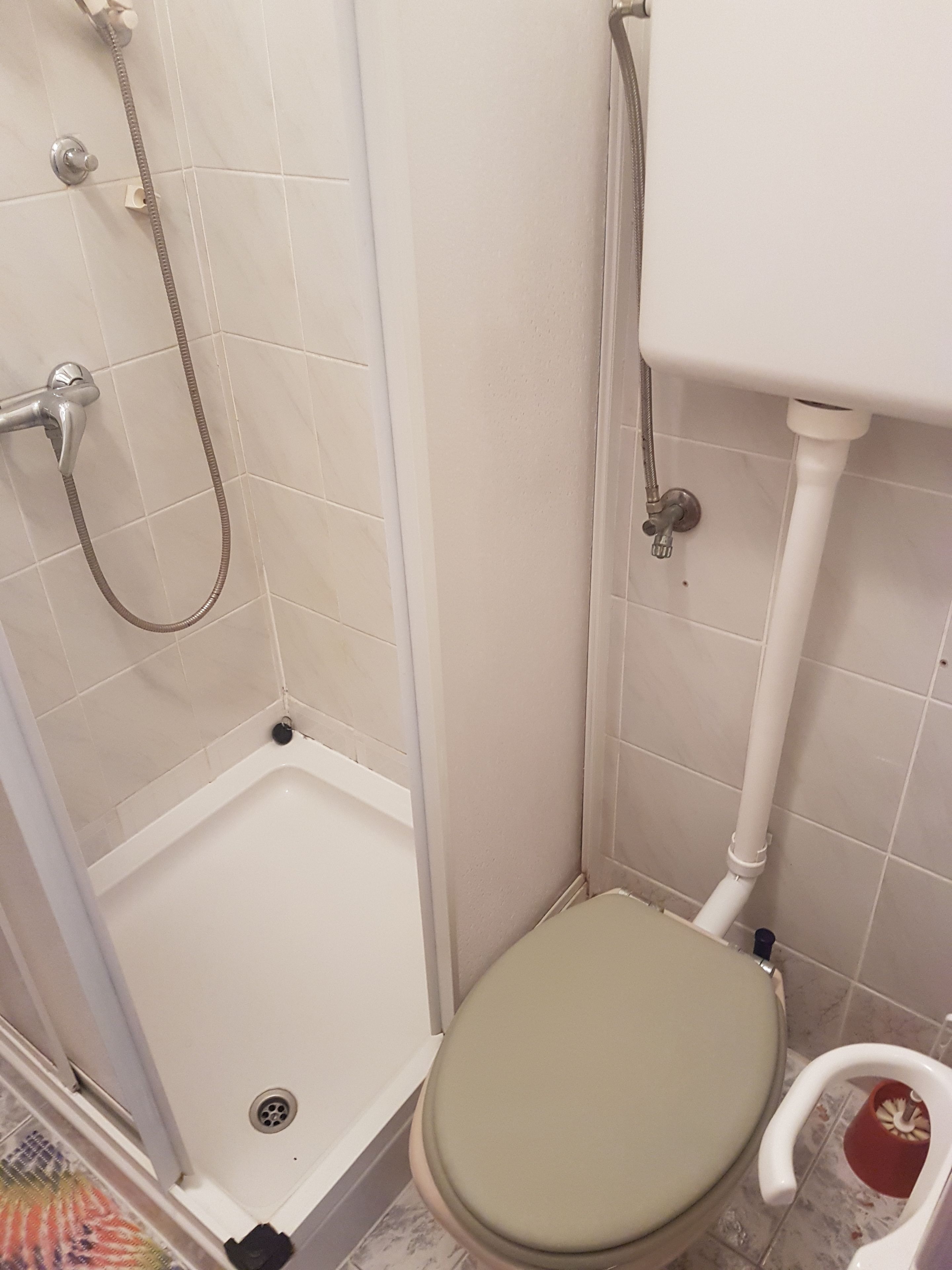 A small bathroom with a shower, toilet, and sink.