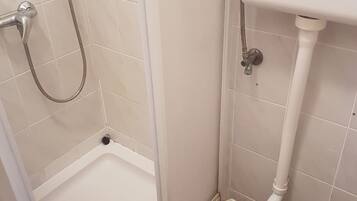 Une petite salle de bain avec une douche, des toilettes et un lavabo.