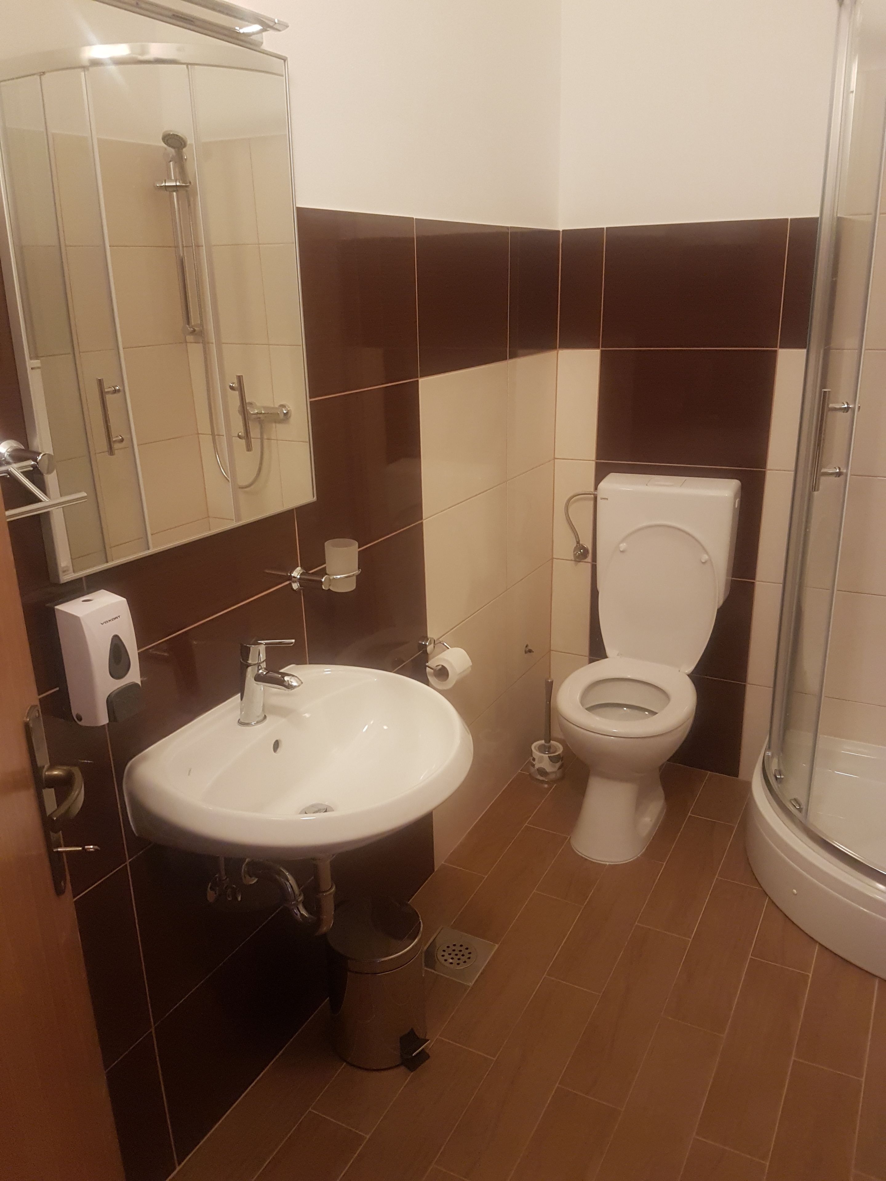 Et badeværelse med vask, toilet og brusebad.
