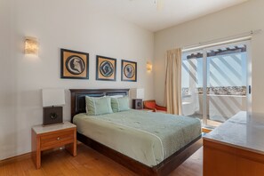 A bedroom with a bed, bedside tables, framed artwork, and a sliding glass door leading to a balcony. - Luna Blanca Villa 04 by Kivoya (Puerto Peñasco)