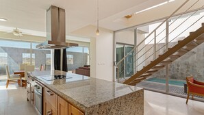 A modern kitchen with granite countertops, stainless steel appliances, and a built-in stove. - Luna Blanca Villa 04 by Kivoya (Puerto Peñasco)