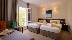 Habitación de hotel con dos camas, un sofá, una silla, un balcón y un cuadro en la pared.