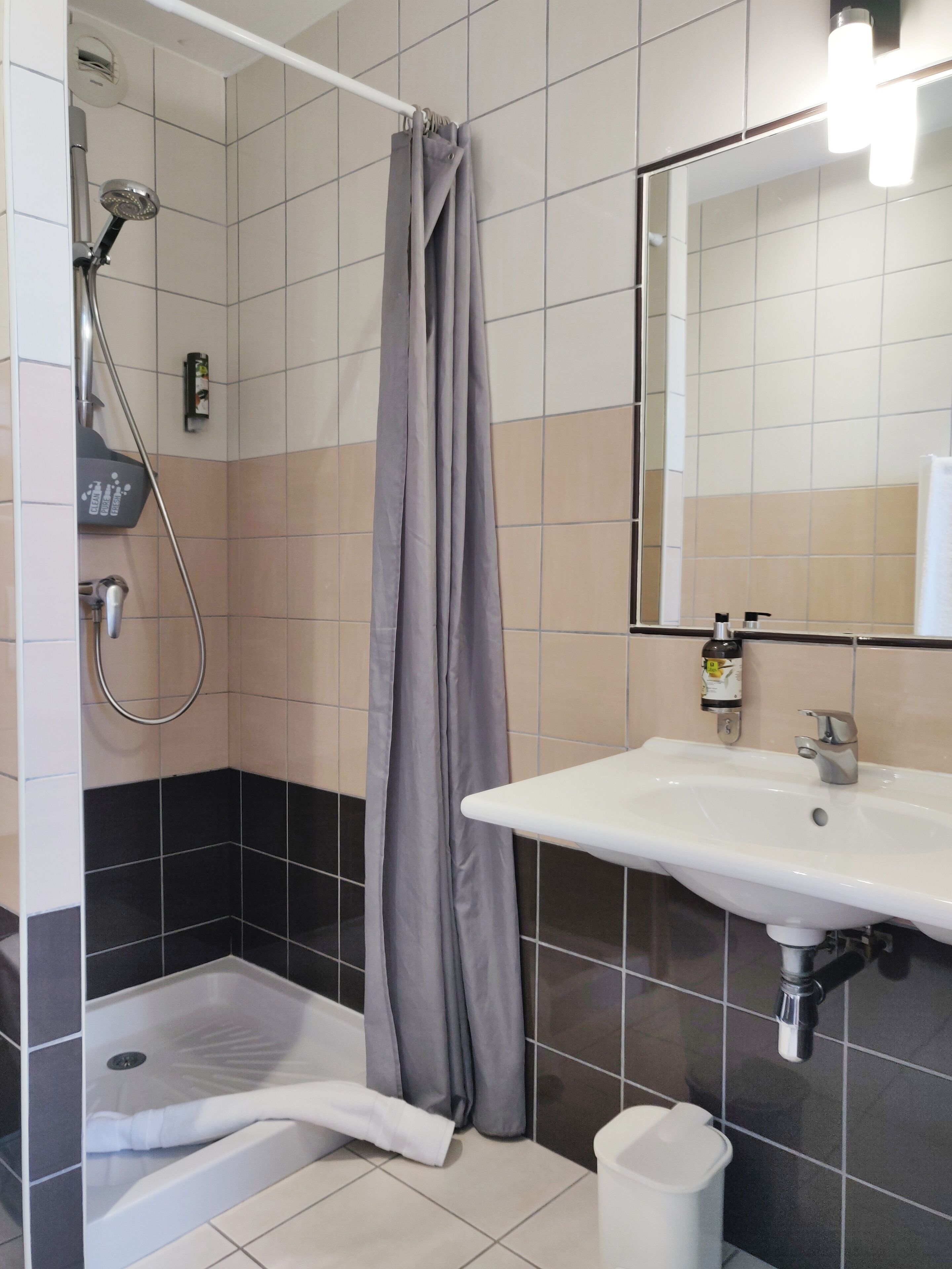 Een badkamer met een bad, douche, wastafel en spiegel.