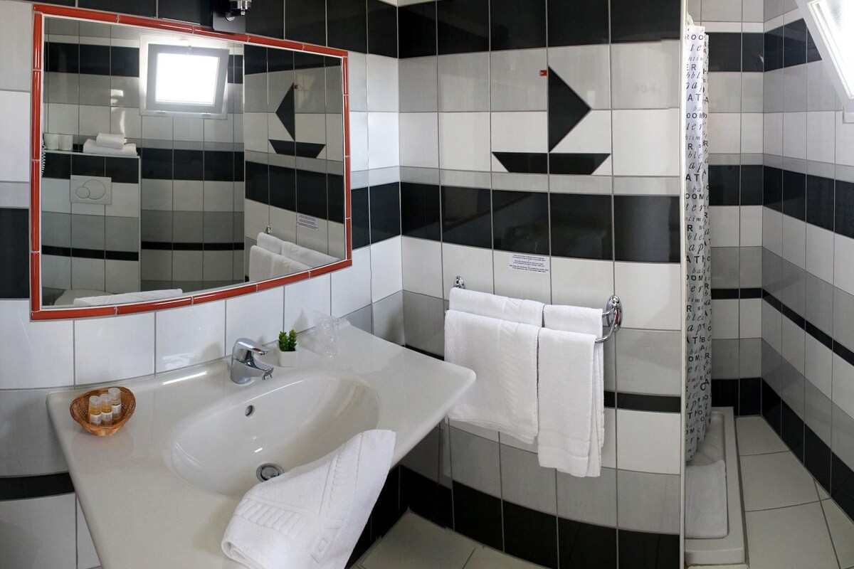A bathroom with a sink, mirror, towel rack, and shower.