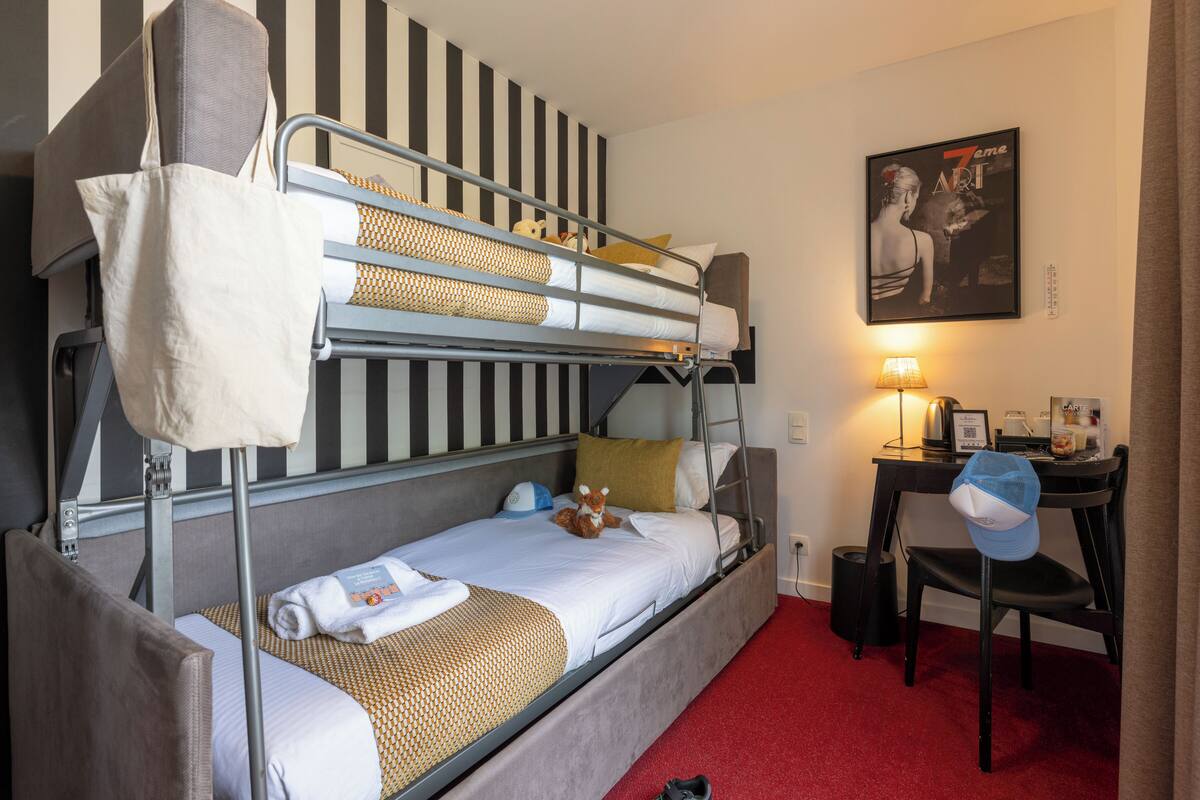 A bunk bed with a desk and chair, a lamp, and a poster on the wall.