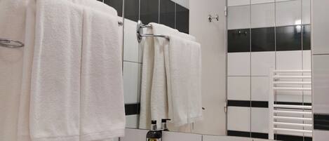 Une salle de bain avec un lavabo blanc, des murs carrelés en noir et blanc, et un miroir au-dessus du lavabo.