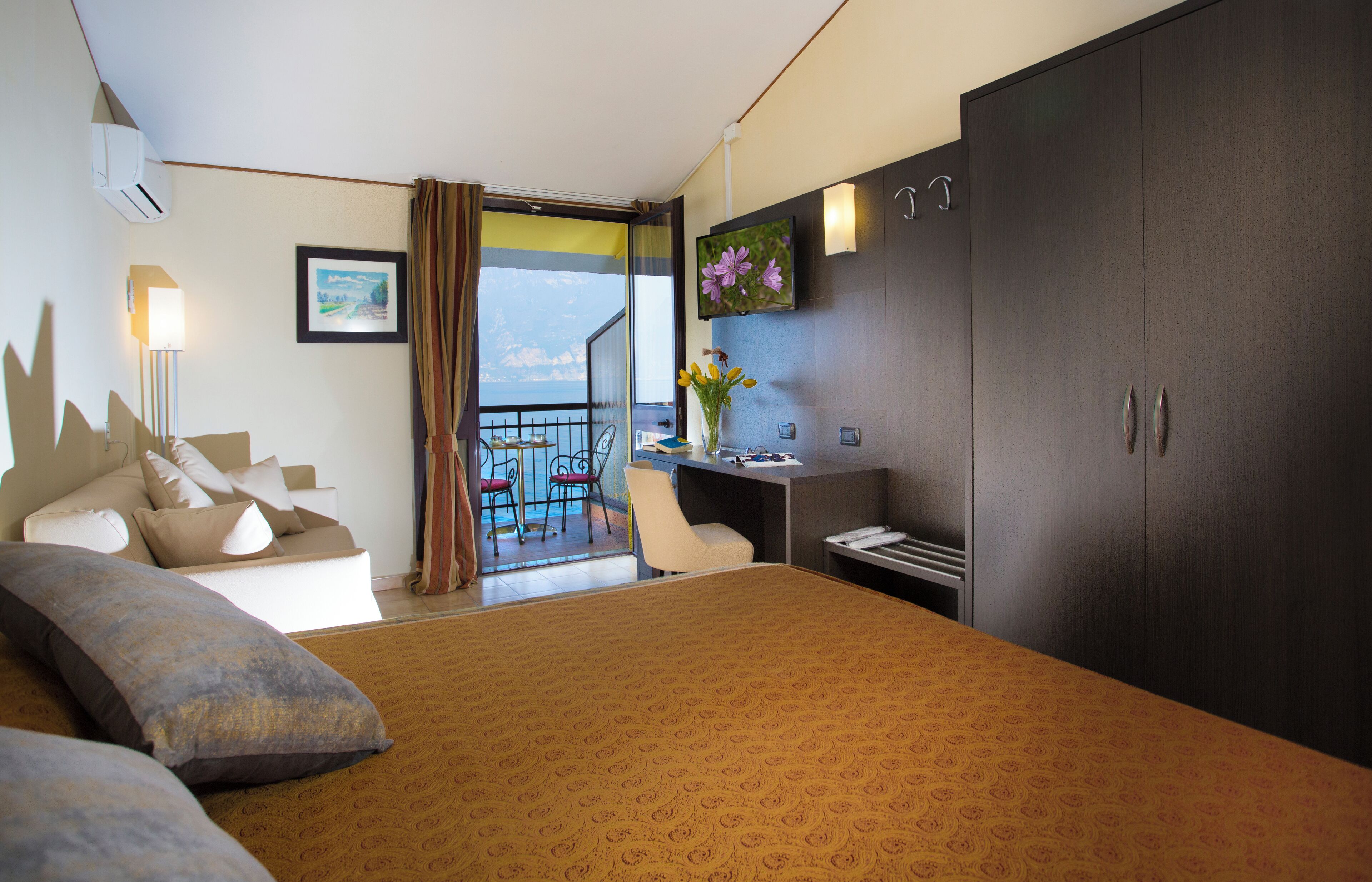 Habitación de hotel con una cama grande, un escritorio, una silla, un armario, un balcón con vistas y un televisor montado.