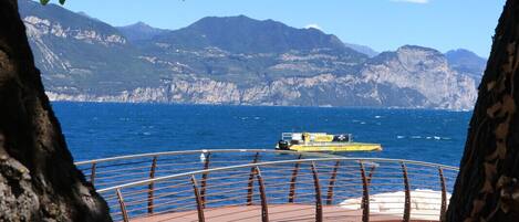 A coastal view with a boat on the water, a stone pathway, and mountains in the background.