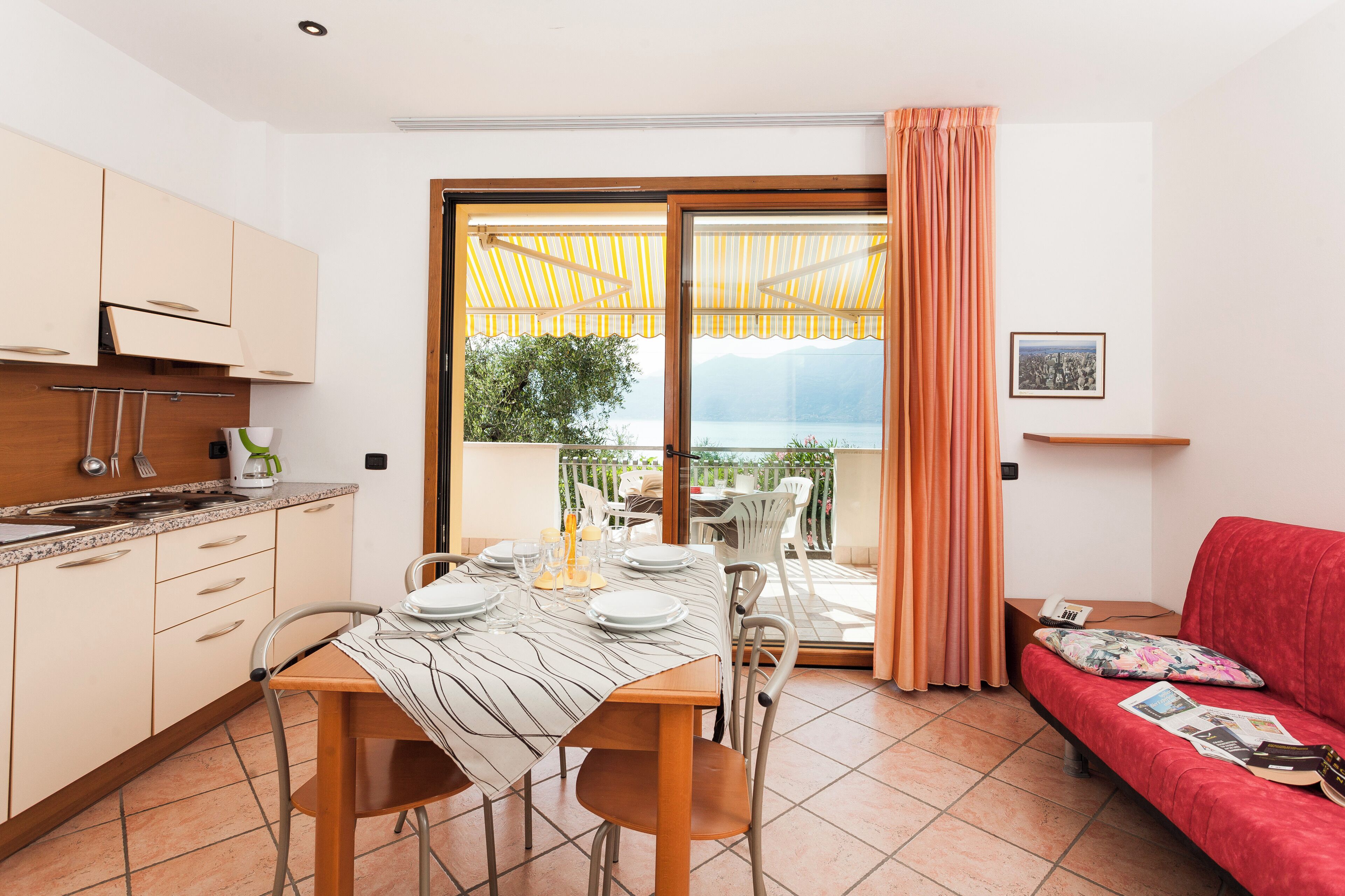 Eine moderne Küche mit Essbereich, einem roten Sofa und einem Balkon mit Blick.
