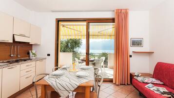 Eine moderne Küche mit Essbereich, einem roten Sofa und einem Balkon mit Blick.