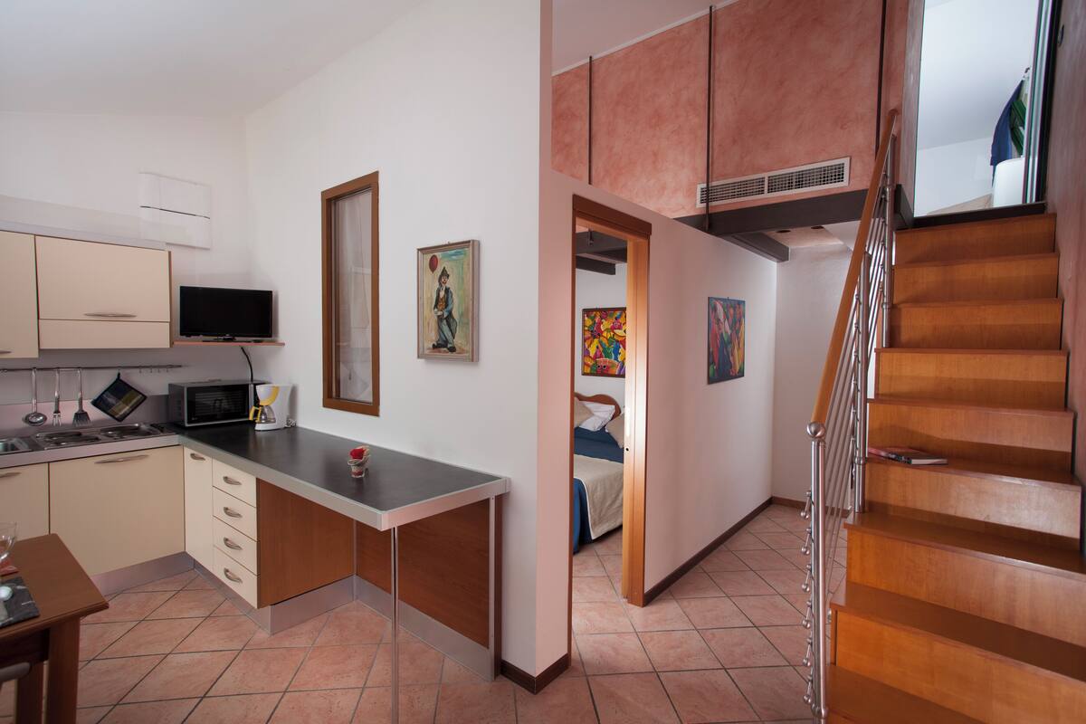 Une cuisine moderne équipée d’un four à micro-ondes encastré, d’une table à manger et d’un escalier menant à l’étage supérieur.