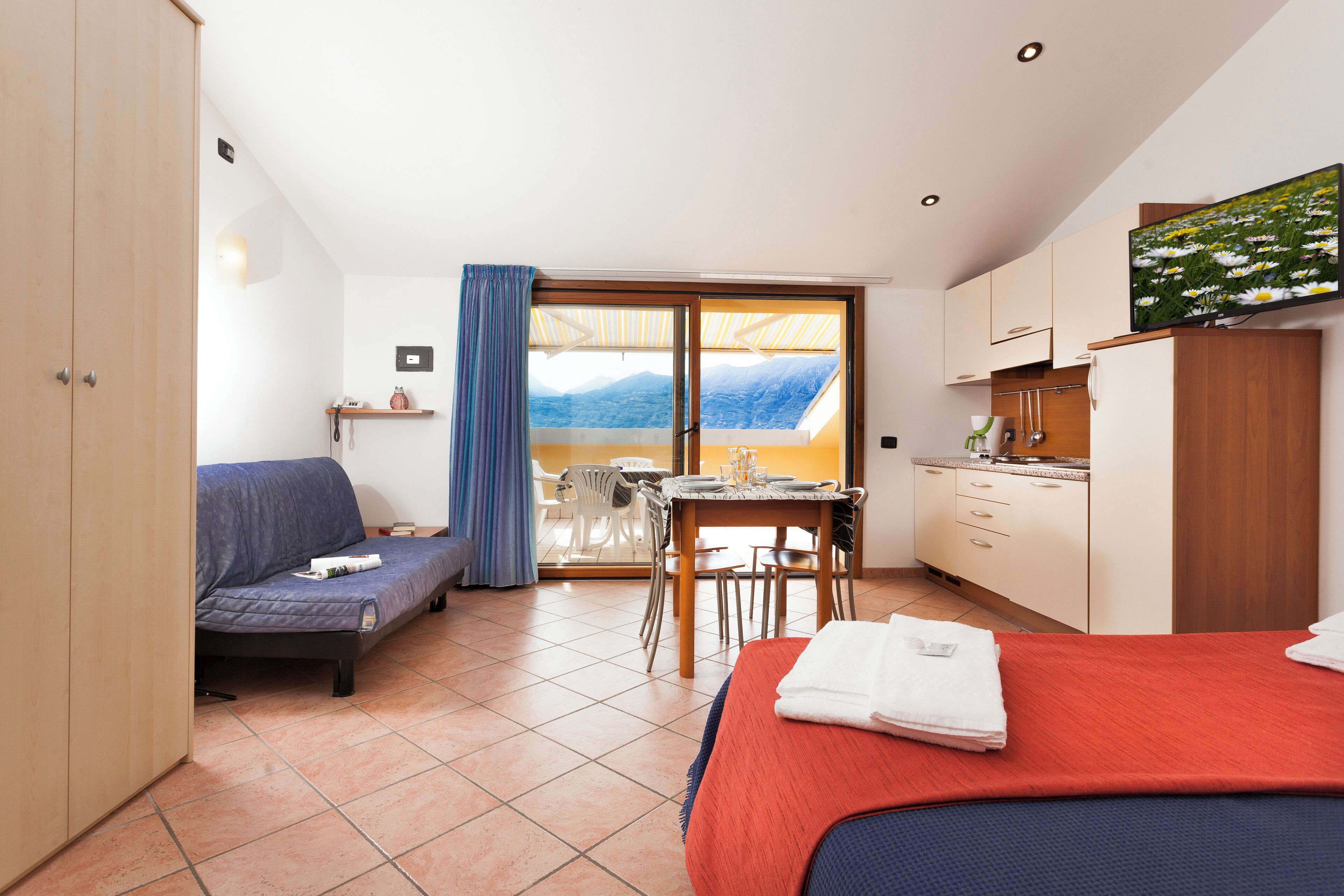 Un dormitorio con cama, sofá, mesa de comedor y zona de cocina.