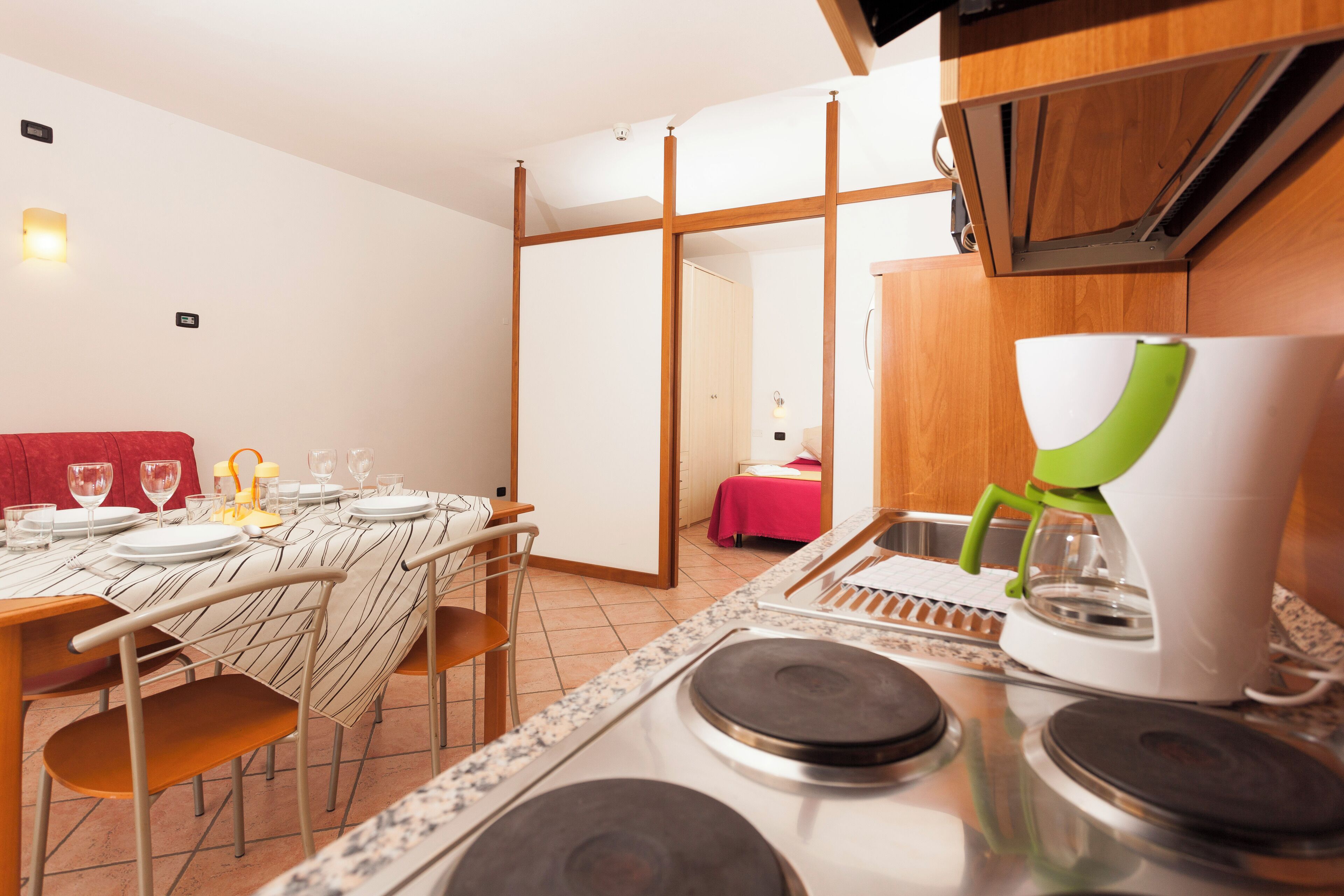 A modern kitchen with a dining area, wooden cabinets, and a coffee machine.