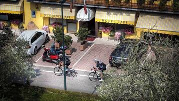 Un hotel con fachada amarilla, un letrero para restaurante y un estacionamiento con coches y bicicletas.