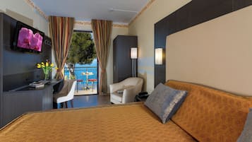 A hotel room with a bed, a desk, a chair, a TV, and a view of the outdoors.