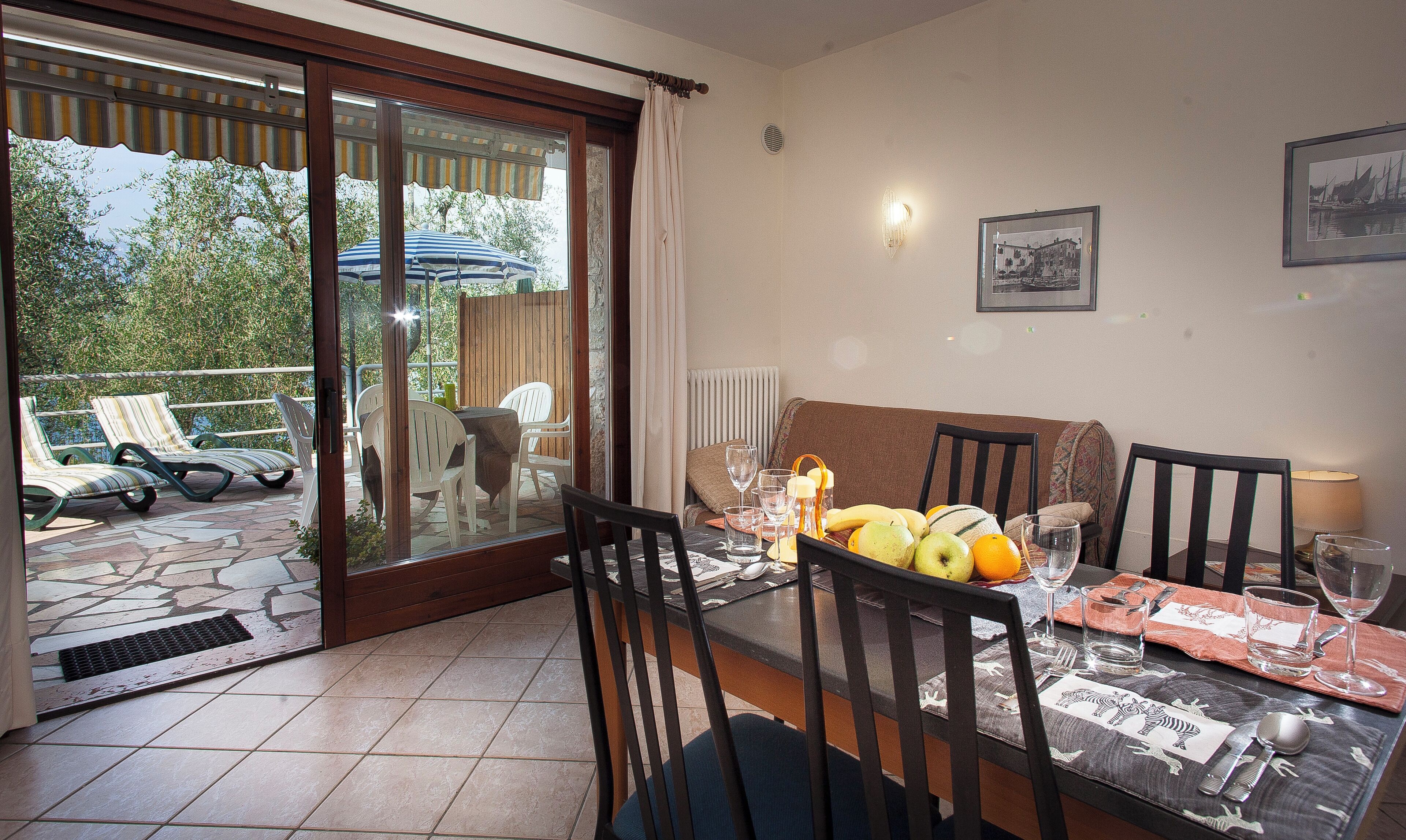 A dining area with a table set for four, chairs, a glass of water, and a fruit bowl.