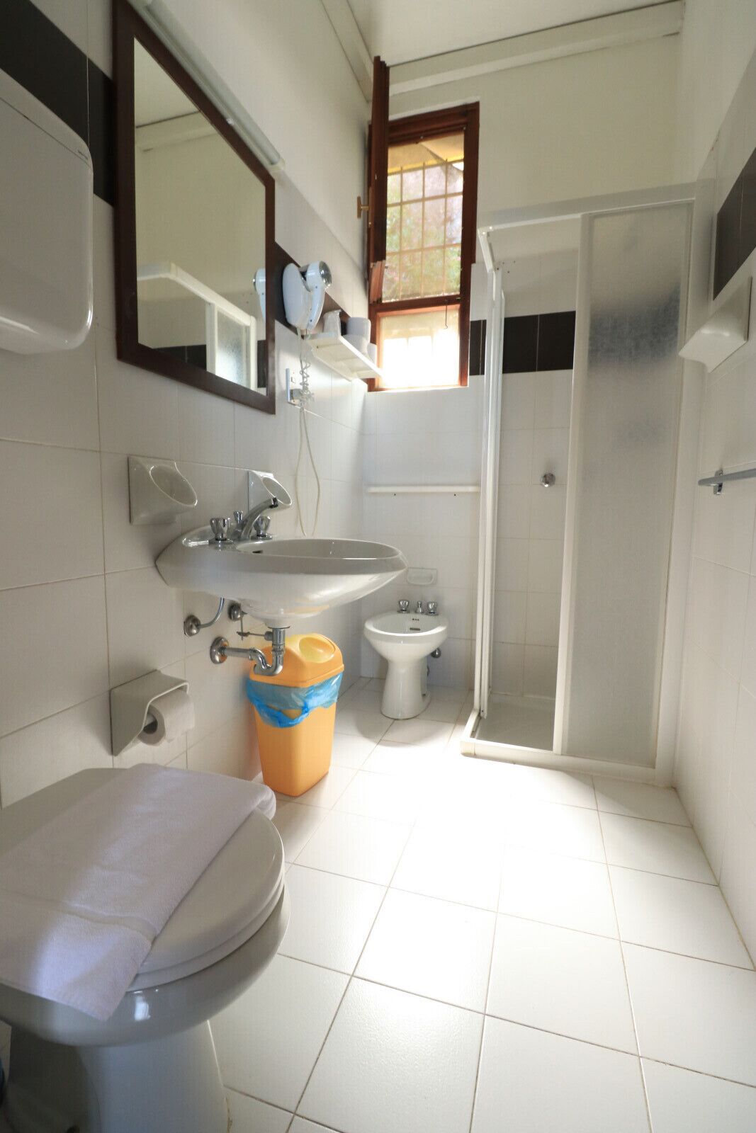 A bathroom with a toilet, sink, bidet, and shower.