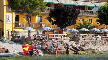 Un hôtel situé sur la côte, doté d’une terrasse, d’une piscine et d’un rivage rocheux.
