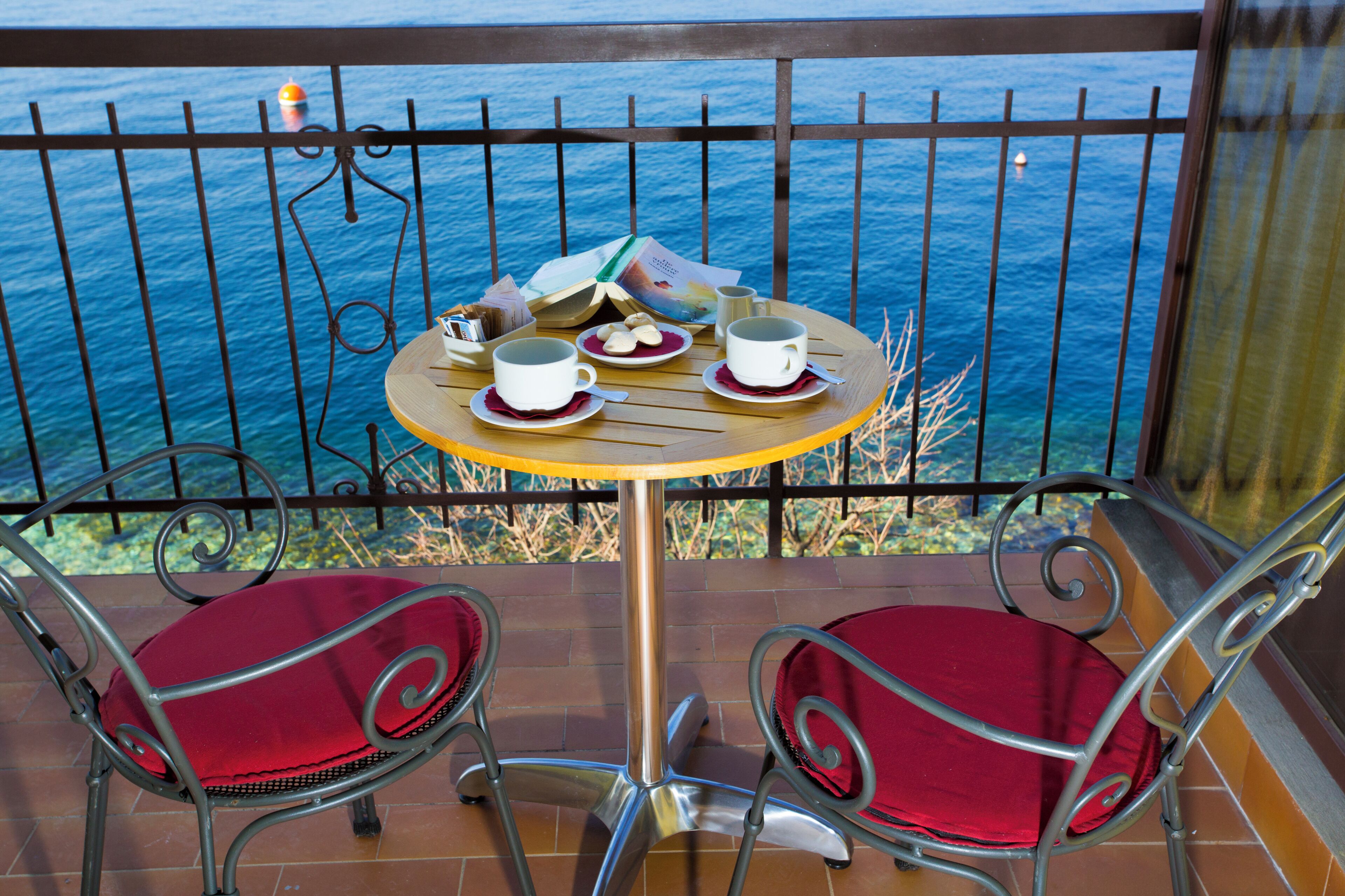 Un balcone con un tavolo apparecchiato per due persone, vista su un corpo d'acqua.